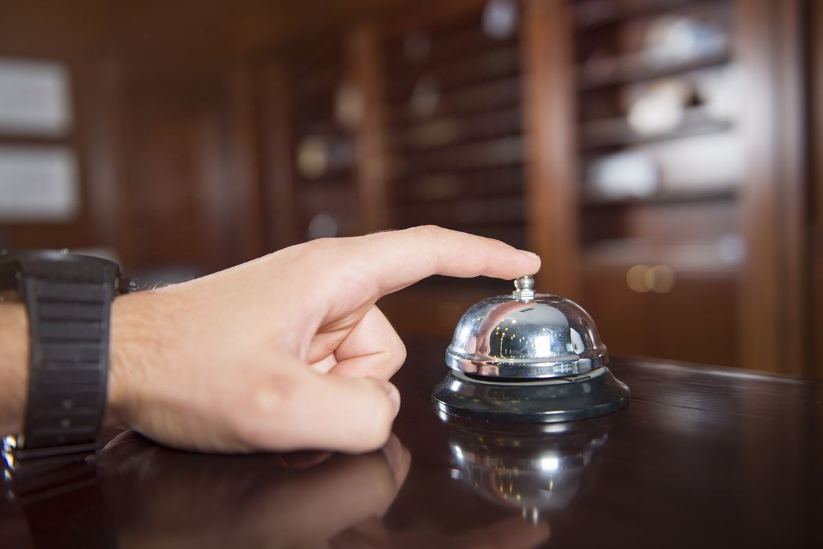 A service bell in a hotel with a hand on it.